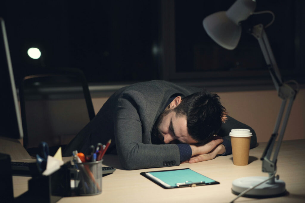 Burned-out business owner asleep at desk, illustrating the hidden cost of business growth.
